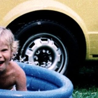 Two children playing in backyard with inflatable pool.