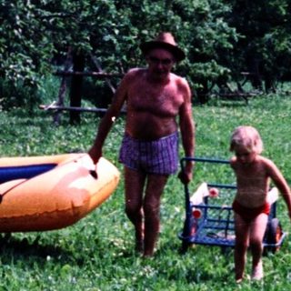 Family preparing inflatable boat near grassy lakeside.
