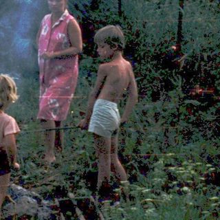 Family gathering around an outdoor campfire.