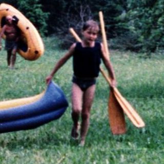 Children playing with inflatable slide in orchard.