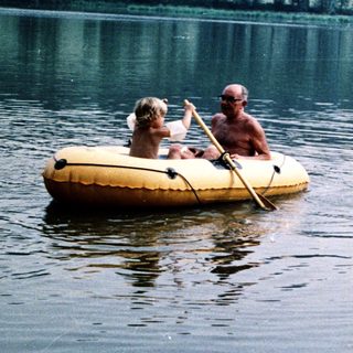 Family enjoying paddle boating on calm lake.