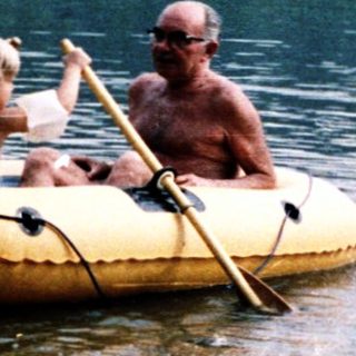 Family enjoying paddle boating on calm lake.