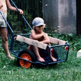 Two children pushing a wagon in a backyard.