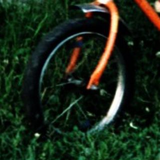 Young child learning to ride a bike with adult assistance.