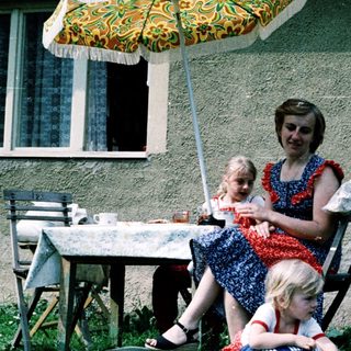Family enjoying outdoor picnic by house.