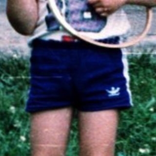 Two children playing with tennis rackets outdoors.