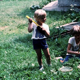 Two children playing with sticks outdoors.