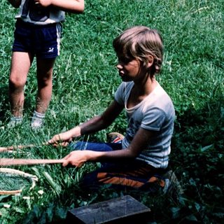 Two children playing with badminton equipment outdoors.