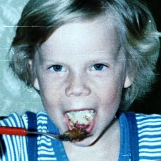 Child eating cake with frosting on face.