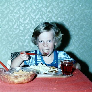 Child eating cake with frosting on face.