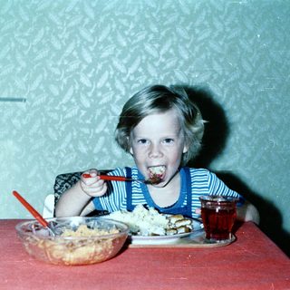 Child eating cake with frosting on face.