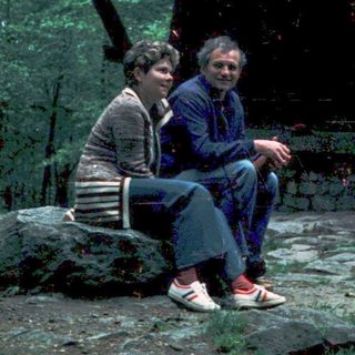Two people sitting together outdoors under a shelter.