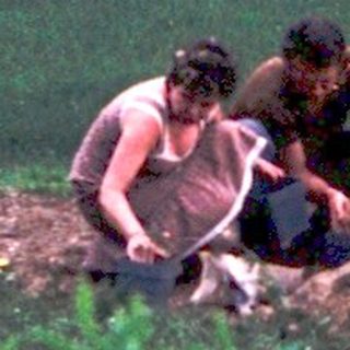 Two people sitting together outdoors in a rural garden.