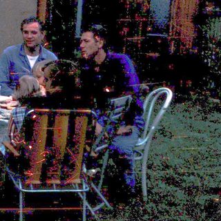 Three men sitting outdoors at a picnic table.