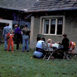 People gathered outside damaged house during cleanup.
