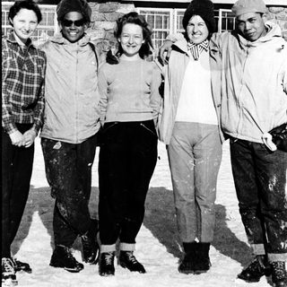Five people posing together outdoors in winter clothing.