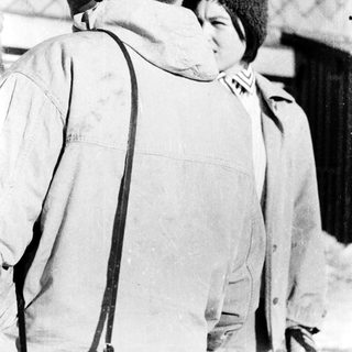 Two people wearing winter clothing standing closely outdoors.