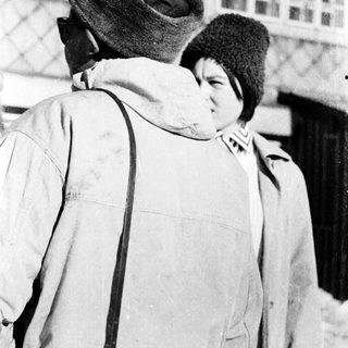 Two people wearing winter clothing standing closely outdoors.