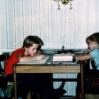 Two children studying together at a table indoors.