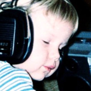 Child listening to music with headphones on floor.