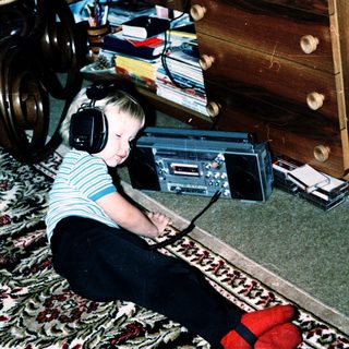Child listening to music with headphones on floor.