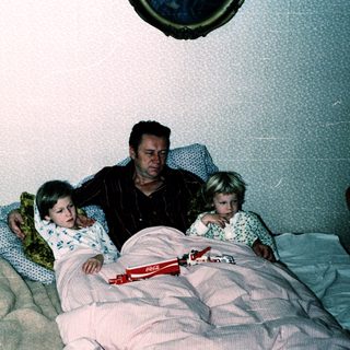 Family sharing bed with children at night.