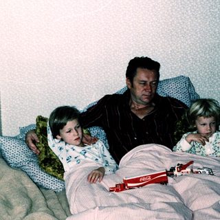 Family sharing bed with children at night.