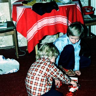 Two children playing with a toy train set.