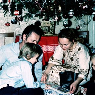 Family playing board game indoors during holiday season.