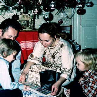 Family playing board game indoors during holiday season.