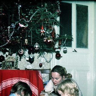 Family opening Christmas presents by decorated tree.