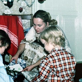 Family opening Christmas presents by decorated tree.