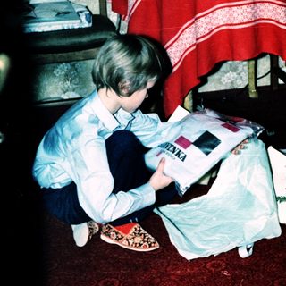 Two children opening wrapped gifts indoors.