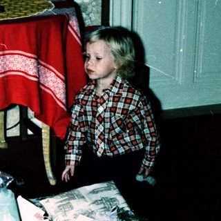 Two children opening wrapped gifts indoors.