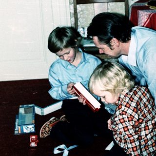 Family reading book together indoors during holiday season.