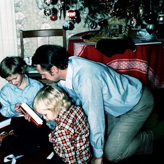 Family reading book together indoors during holiday season.