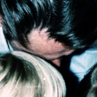 Family members gathered closely indoors, embracing affectionately.