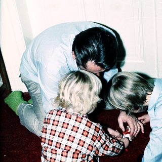 Family members gathered closely indoors, embracing affectionately.