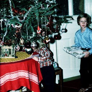 Two children standing near a decorated Christmas tree.