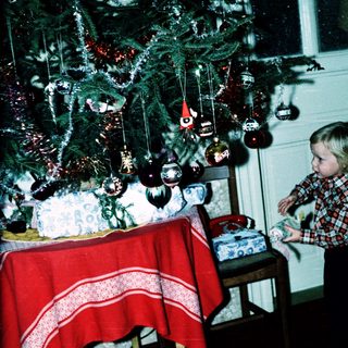 Child decorating Christmas tree with ornaments.