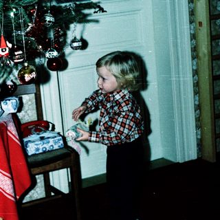 Child decorating Christmas tree with ornaments.
