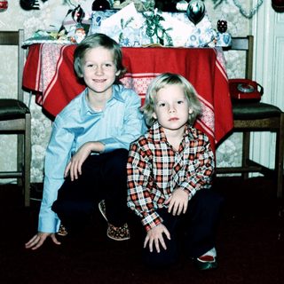 Two children posing near a decorated Christmas tree.