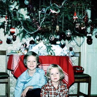 Two children posing near a decorated Christmas tree.