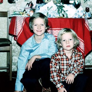Two children posing near a decorated Christmas tree.