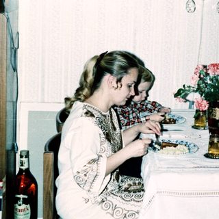 Family dining together indoors with plates and flowers.
