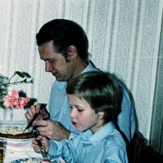 Family dining together indoors with plates and flowers.