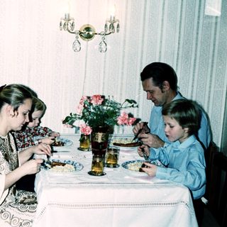 Family dining together indoors with plates and flowers.