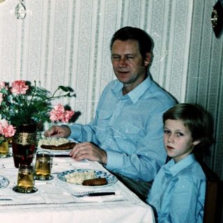 Family dining together indoors during the 1980s.