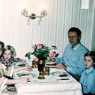 Family dining together indoors during the 1980s.