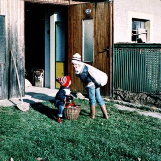 A woman helps a child with a basket outdoors.